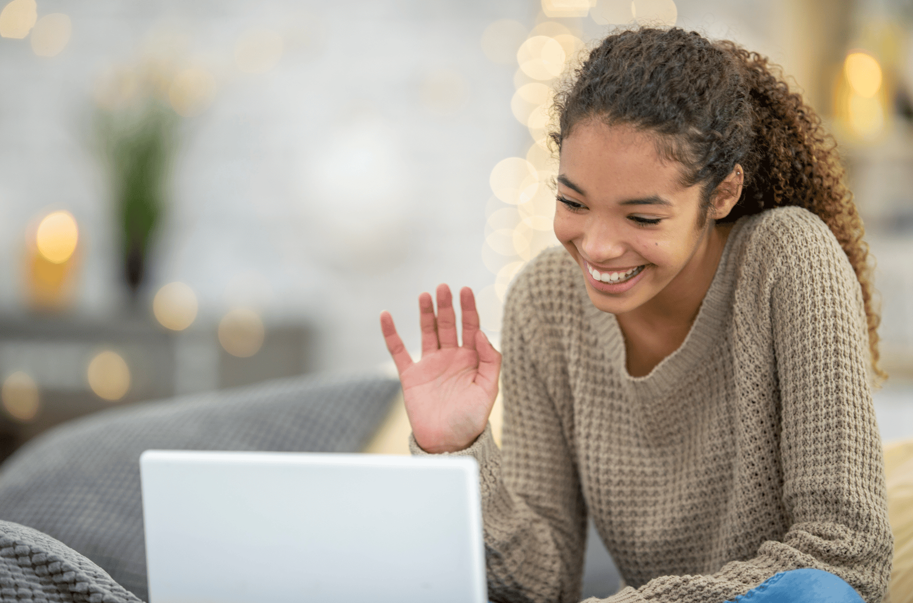 Female student waving and smiling at laptop